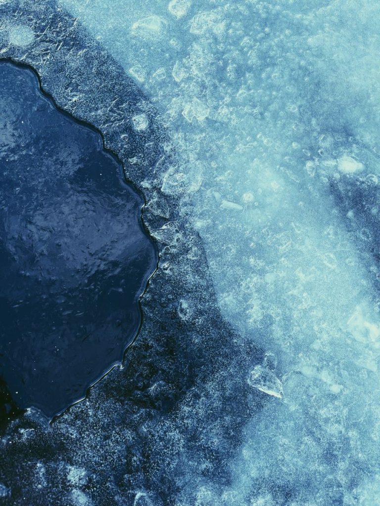 Detailed view of melting ice with textures and cracks, representative of winter thaw.