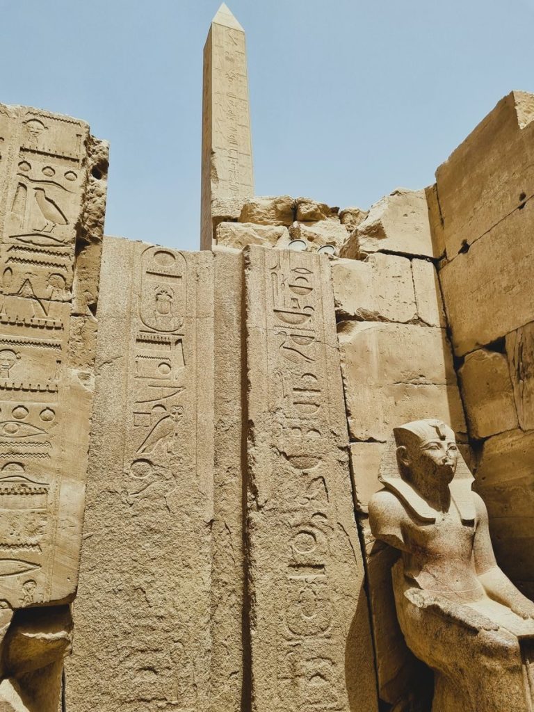Explore ancient Egyptian ruins with hieroglyphs, sculptures, and a towering obelisk.