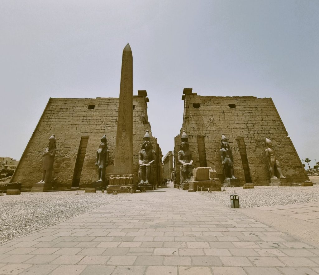 A captivating view of the ancient Luxor Temple with towering obelisks and statues under a clear sky.