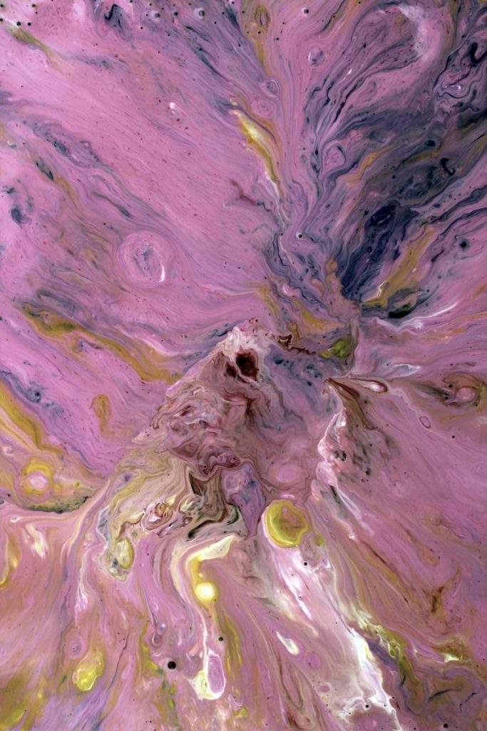 Dynamic abstract art depicting swirling pink liquid with splashes of yellow and purple.