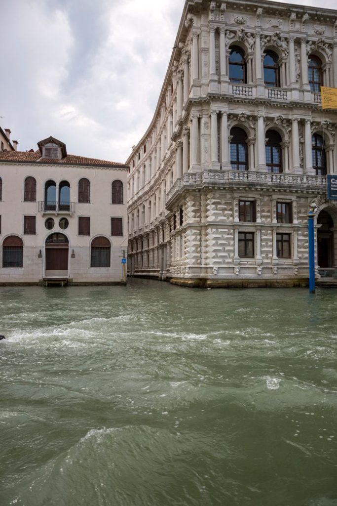 Intricate historic buildings beside a Venetian canal, showcasing classic architecture amidst flowing water.