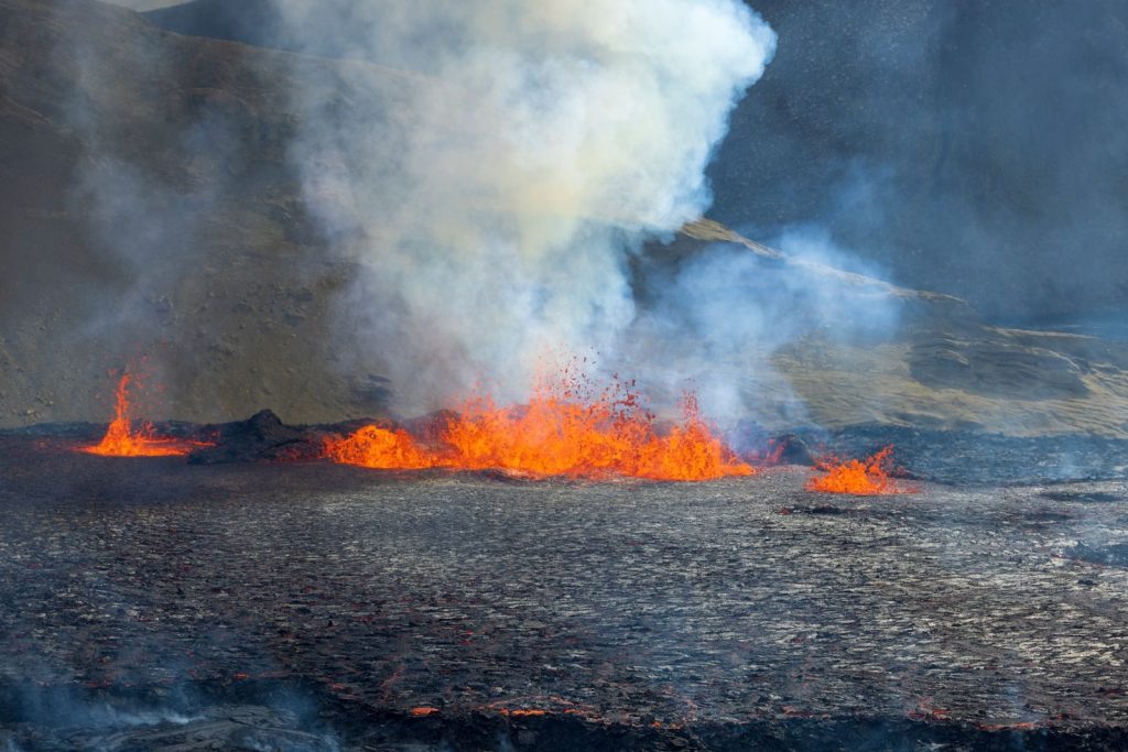 Dramatic eruption showcasing vibrant lava flow and smoke at an active volcano.