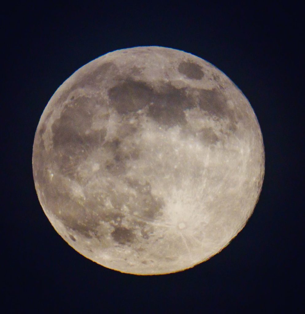 Close-up of full moon against a dark, clear night sky.