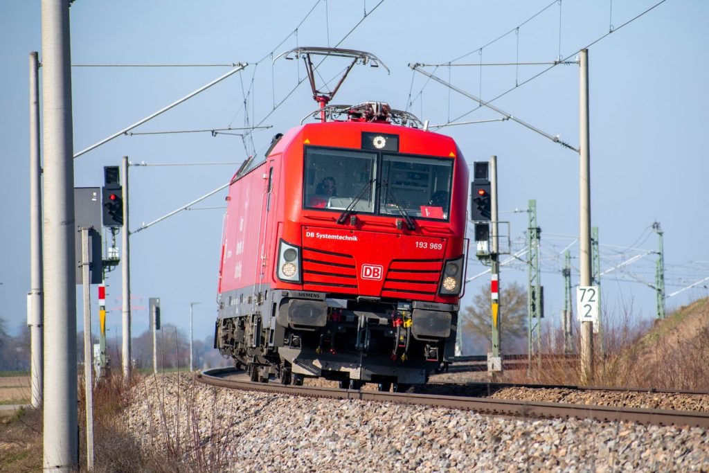 Red DB train on railway track in Bavaria, Germany during a clear day.
