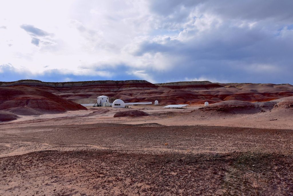 Futuristic habitats set in a Mars-like desert landscape with dramatic sky.