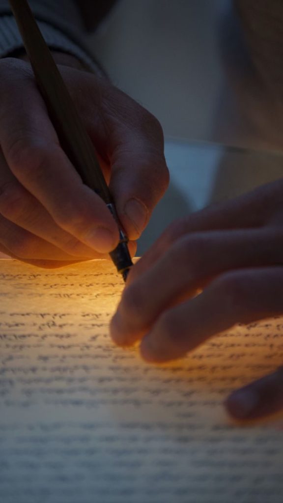Artistic capture of handwriting on glowing paper with traditional quill.