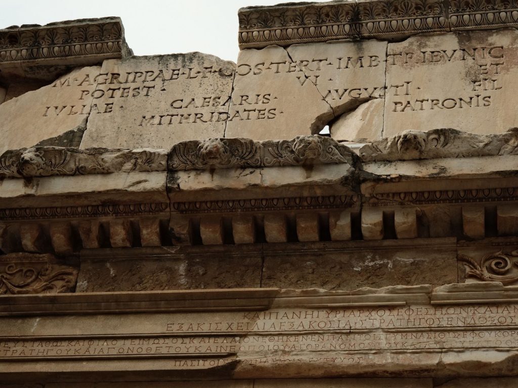 Close-up of ancient Roman architecture featuring Latin inscriptions carved into stone.