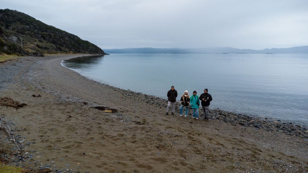 A group of adults enjoying a serene beach view in Ushuaia, Argentina. Perfect for travel and nature themes.