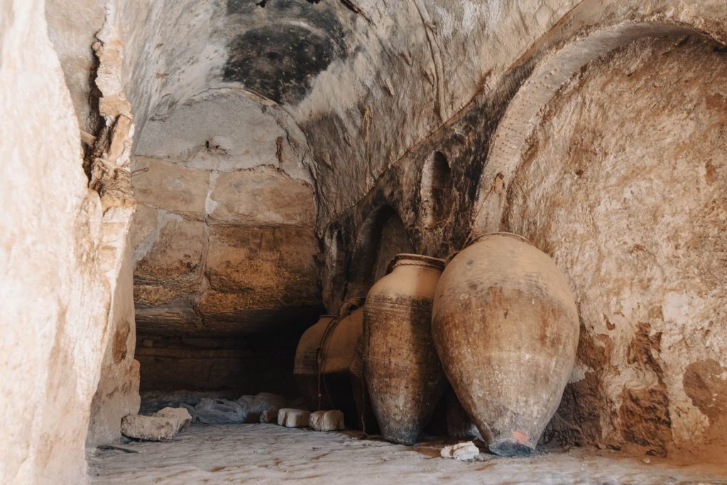 Explore the historic charm of an ancient cave with large clay jars in Tunisia's unique landscape.