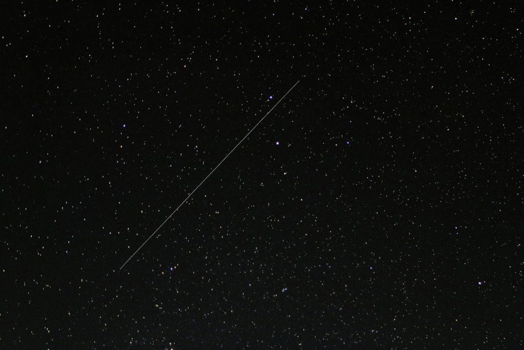 Captivating starry night sky with a visible shooting star streaking across the cosmic backdrop.