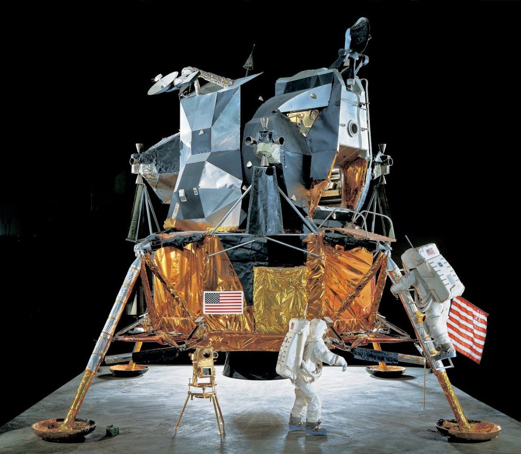 Two astronauts stand near a lunar module
