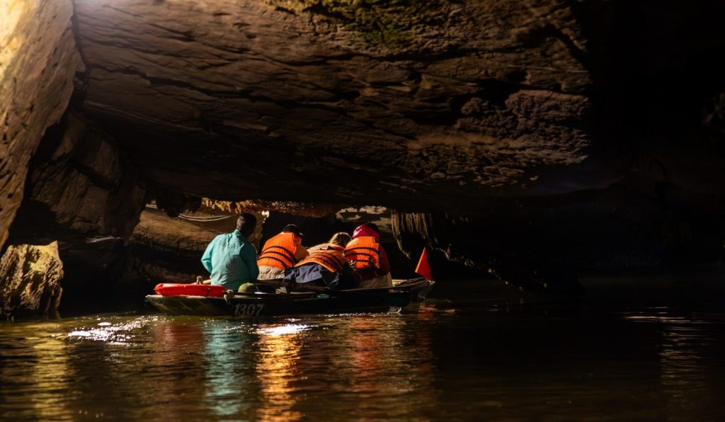 People in a boat sailing through a dark cave