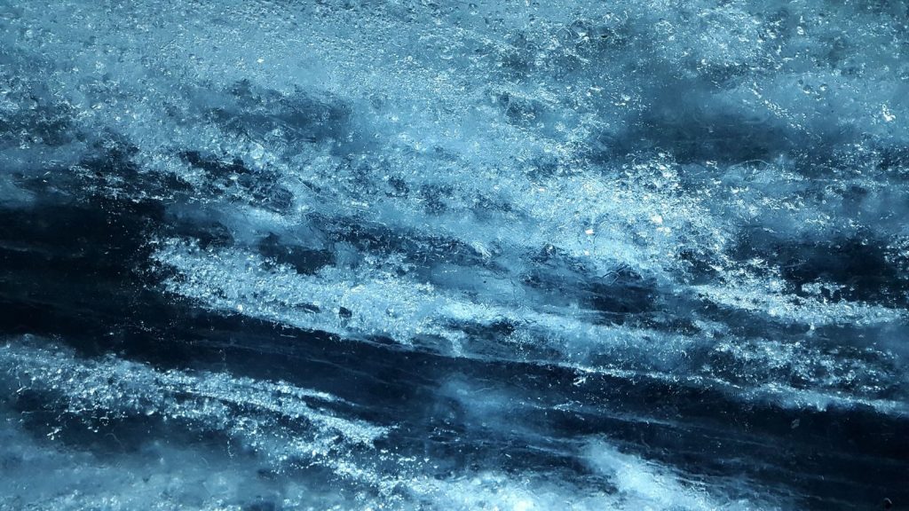 Close-up view of textured blue ice surface, capturing abstract natural patterns.