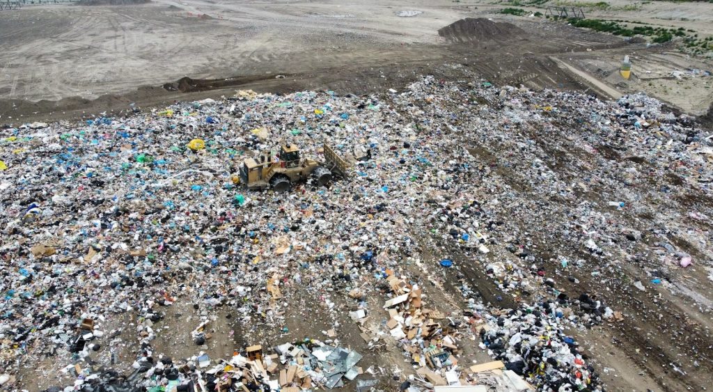 Bulldozer compacting trash at a large landfill site.