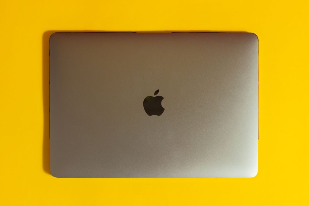 A modern laptop with a sleek design on a bright yellow surface, emphasizing minimalism.