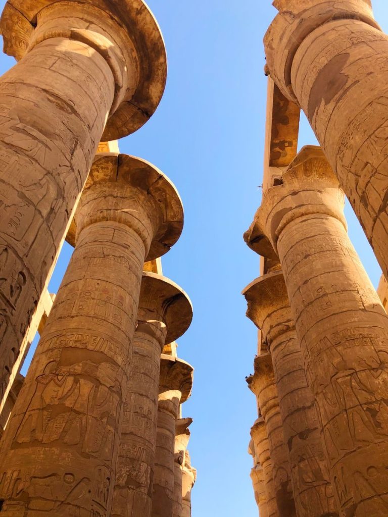 Stunning view of ancient stone columns at Karnak Temple, Luxor, Egypt, under a clear blue sky.