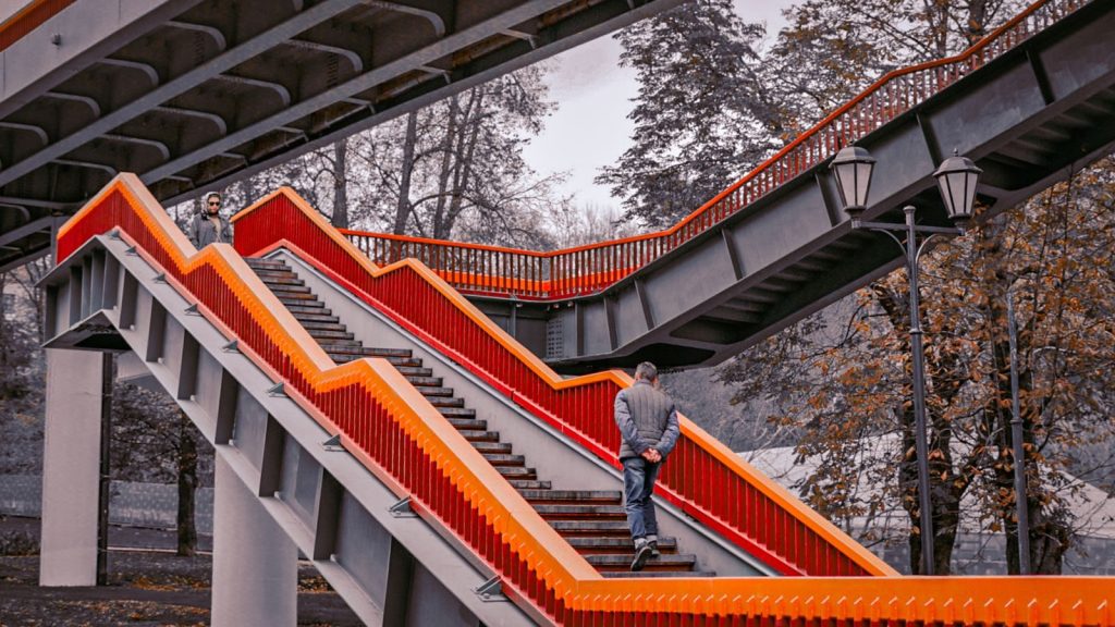 A striking red staircase with people in an urban park, showcasing unique architectural design.
