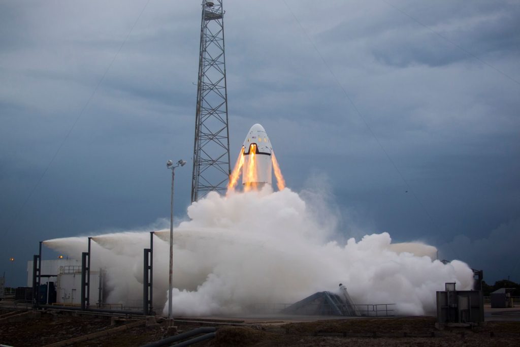 A dramatic rocket launch emitting flames and smoke against a cloudy evening sky, showcasing modern aerospace technology.