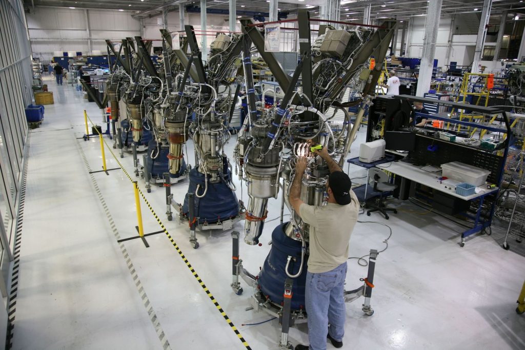From above back view of unrecognizable male technician checking details of new spaceship at modern rocket factory
