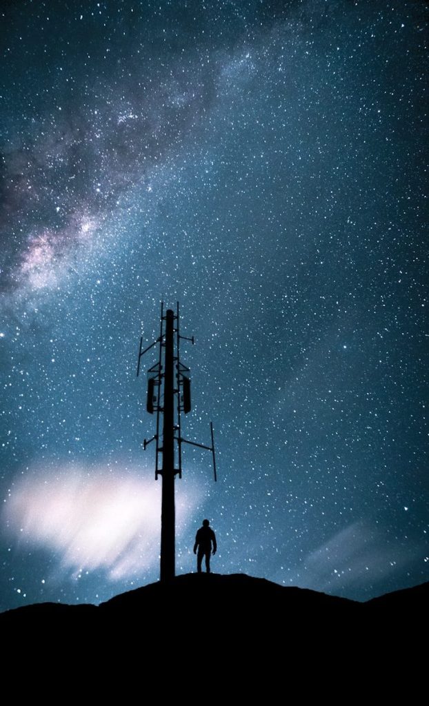 silhouette of people standing on top of electric post under starry night