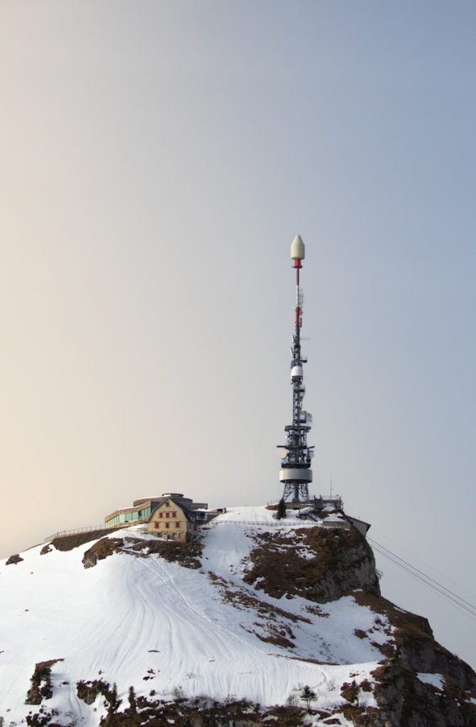 A tall radio tower on a snowy mountain peak.