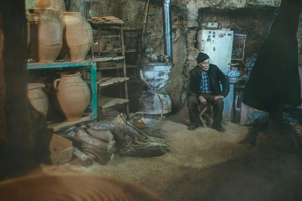 A man sits in a rustic workshop.