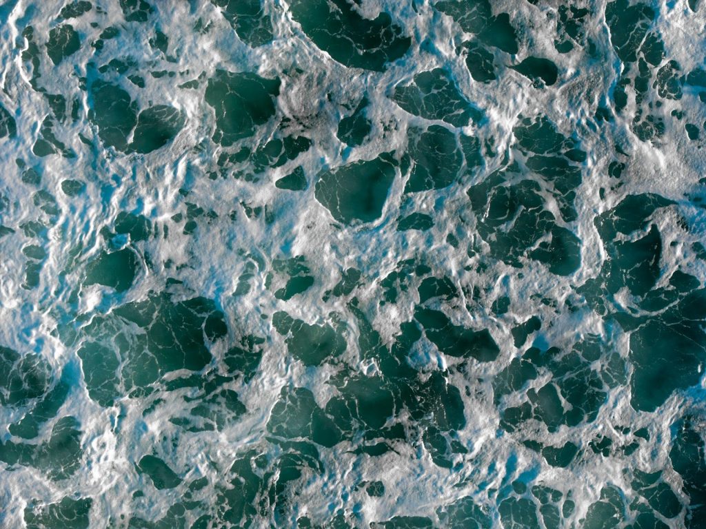 Turbulent ocean water creates a foamy texture.