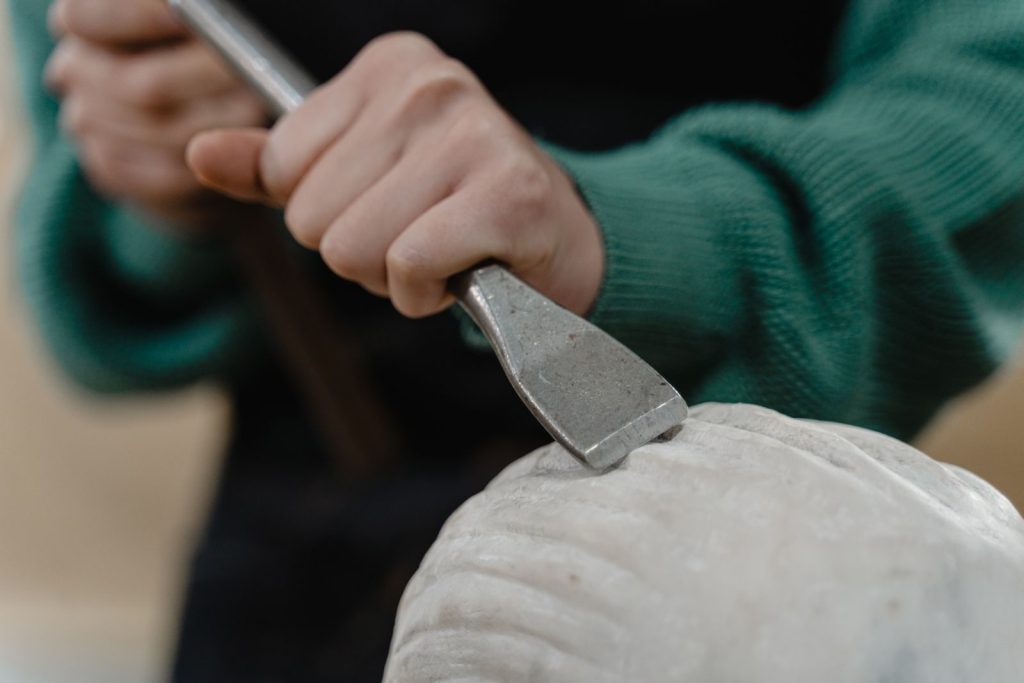 A detailed view of an artisan's hand engraving a piece of stone with precision and skill.