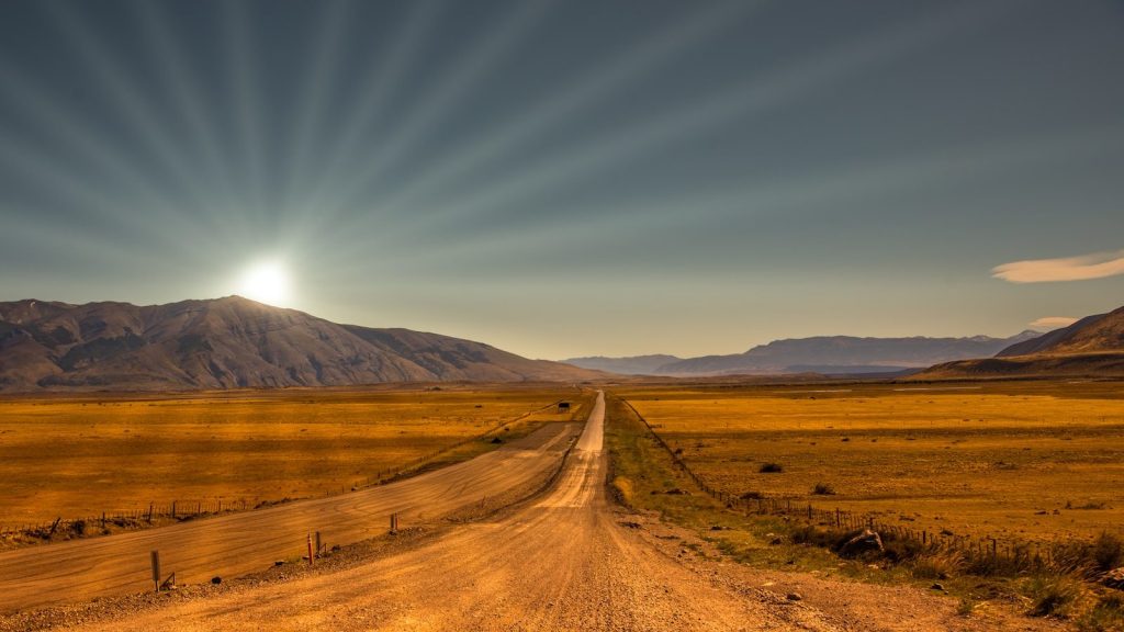brown field near brown mountain under blue sky during daytime