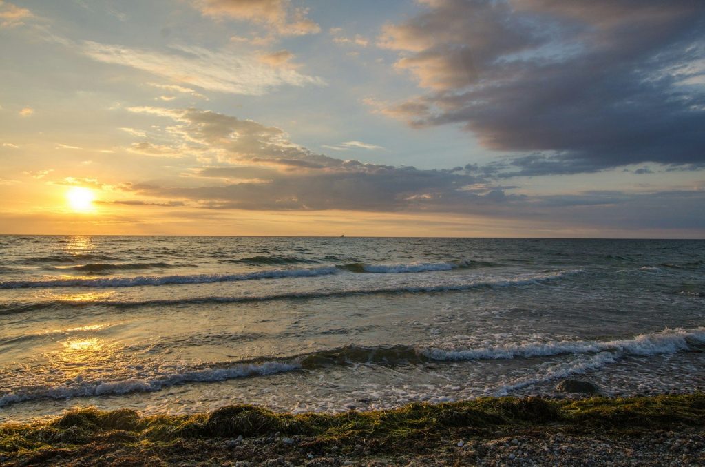 ocean waves crashing on shore during sunset