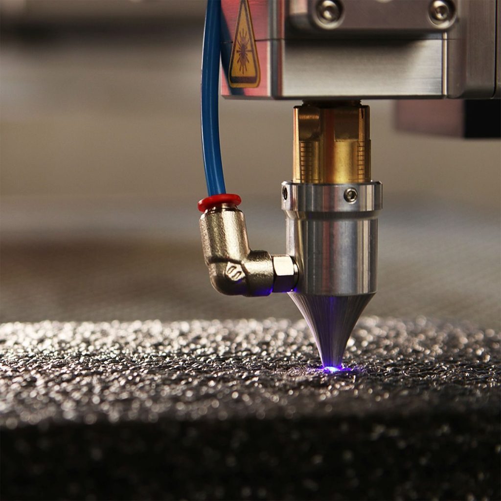 Close-up of a high-precision laser engraver focusing on a textured surface.