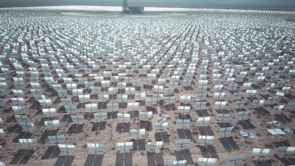 Aerial view of expansive solar panel array in a desert landscape generating renewable energy.