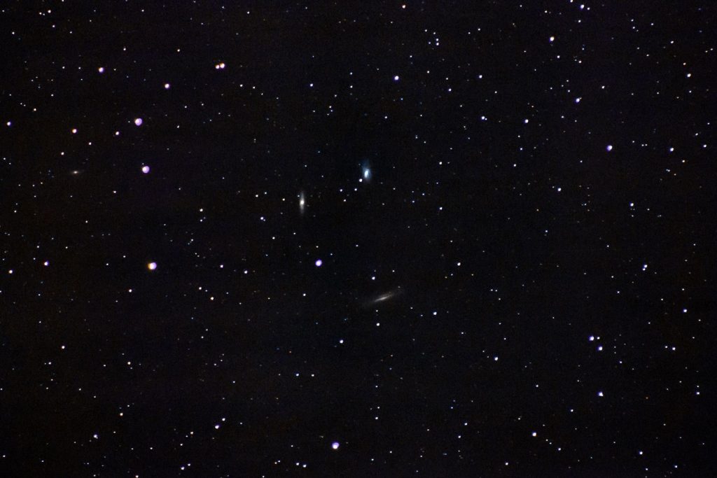 A beautiful wide-angle shot of a clear starry night sky, featuring distant galaxies shimmering brightly.