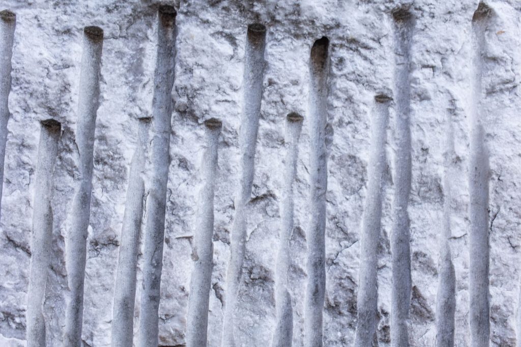 Textured background of uneven surface of gray stone with straight hollow lines on top