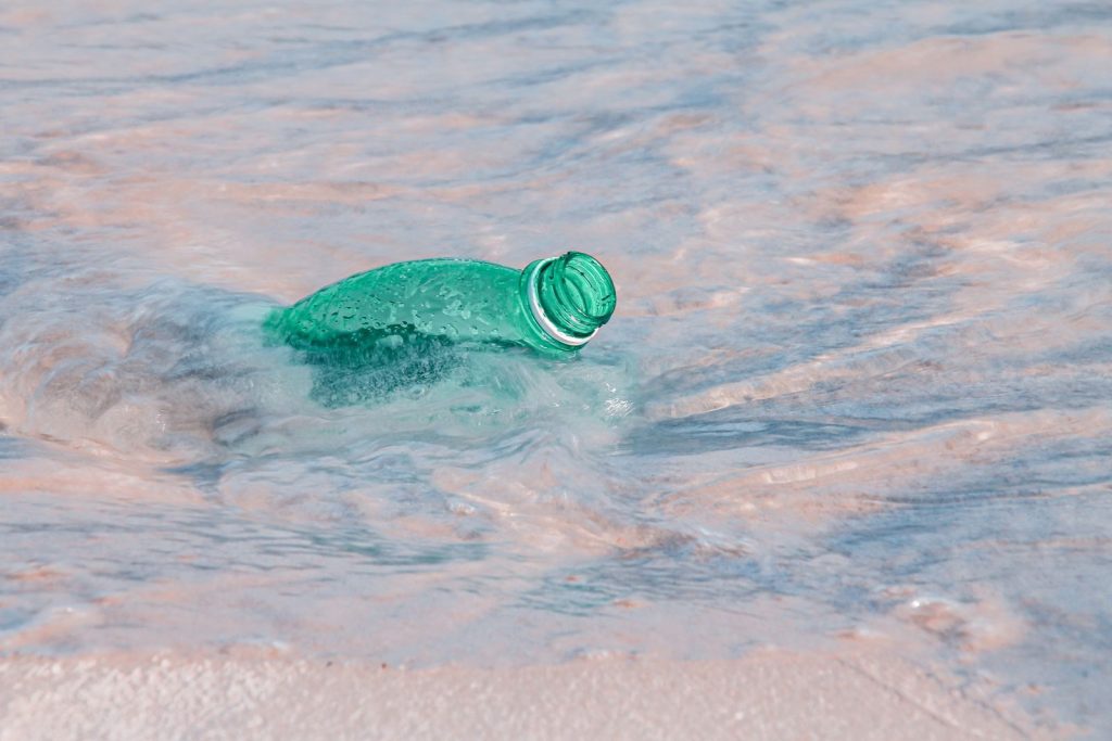 Close-up of a plastic bottle polluting the ocean shore, highlighting environmental issues.