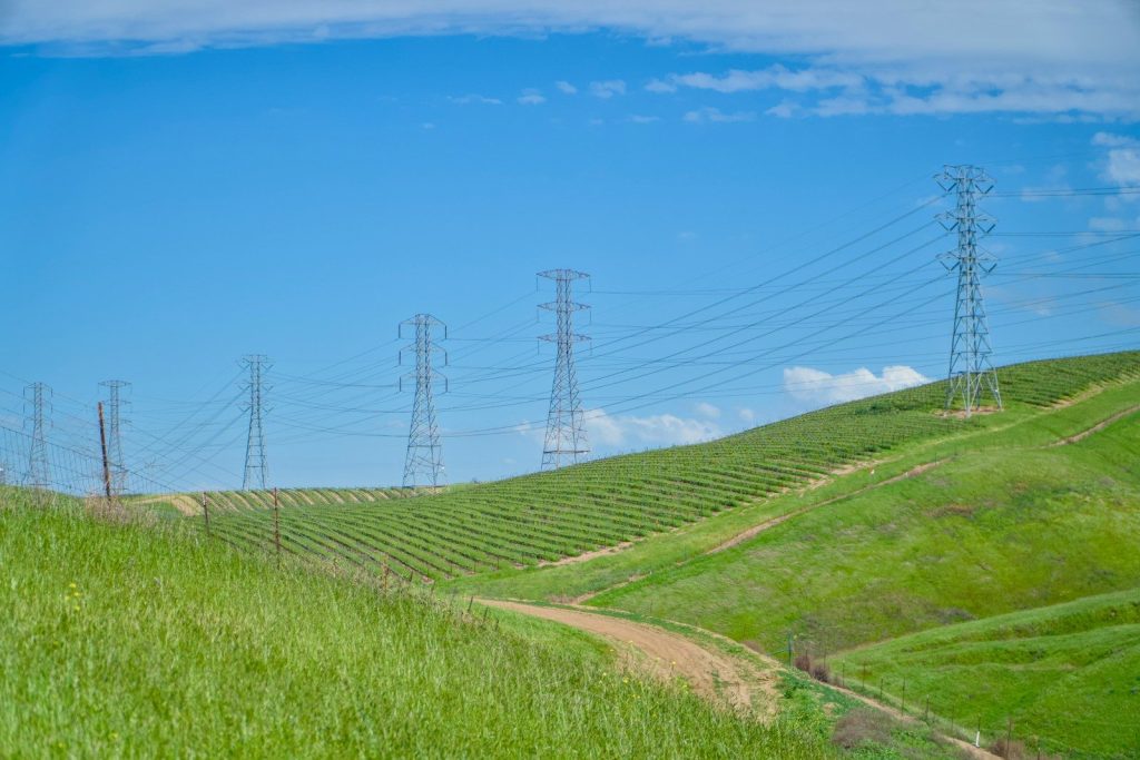 a field of green grass with power lines in the background
