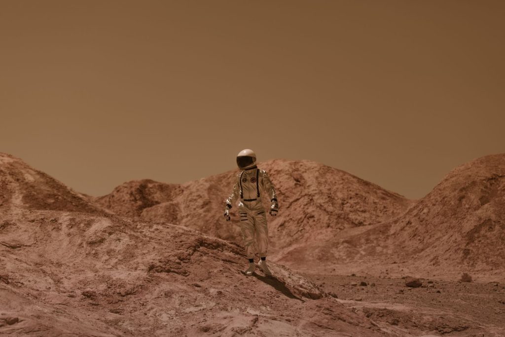 An astronaut in a spacesuit ventures across a barren, Mars-like desert landscape.