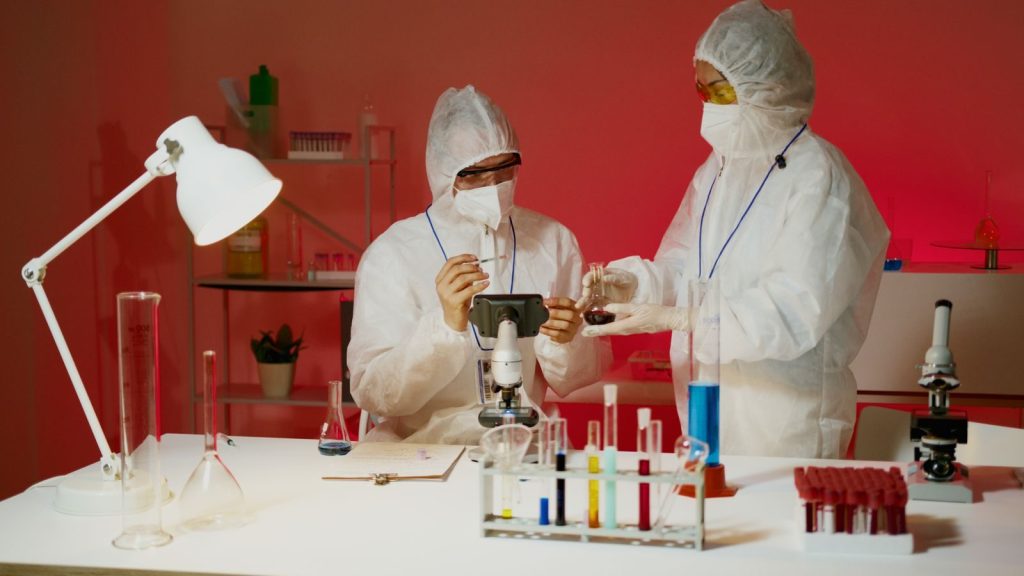 Scientists in protective gear performing lab experiments with microscopes and test tubes.
