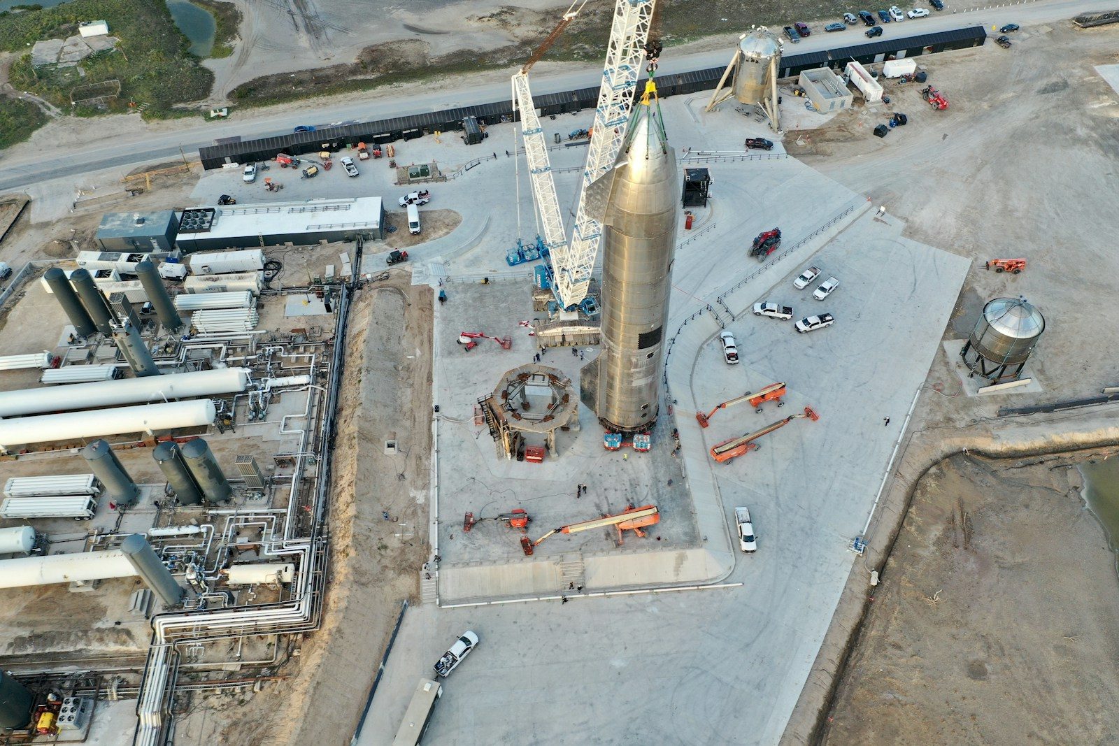 Rocket assembly at a launch facility with cranes and vehicles.