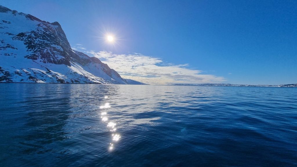 the sun shines brightly over the water of a mountain lake