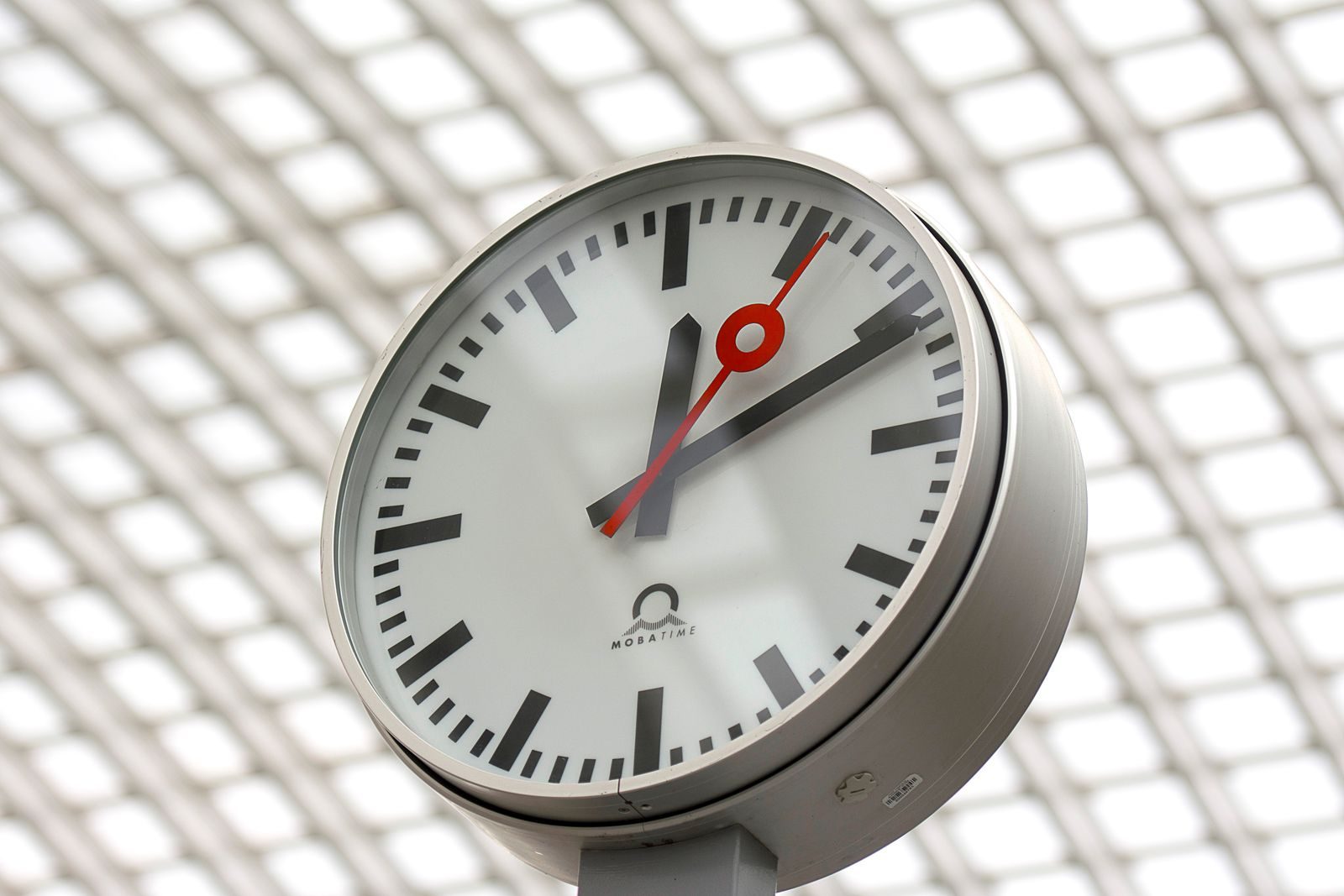 Close-up of a modern analog clock against a geometric background, perfect for time-related themes.