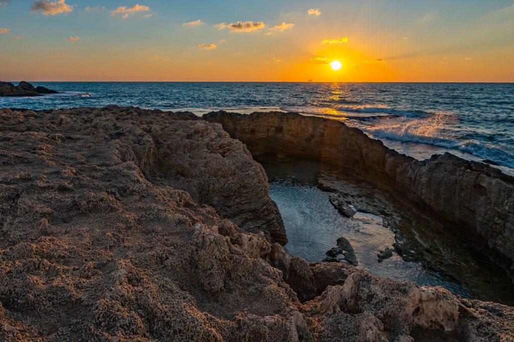 Stunning sunset over rocky coastal formations with tranquil ocean views.