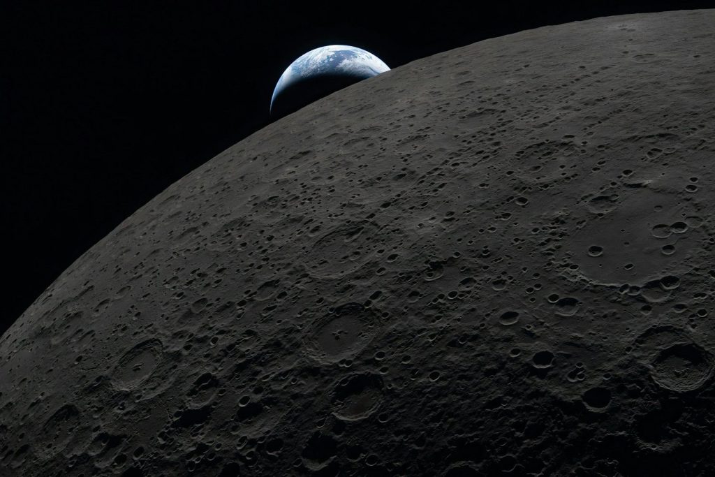 Earth rises over the dark lunar surface