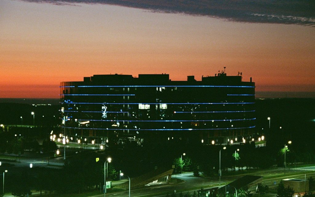 Modern office building illuminated at dusk with sunset sky.