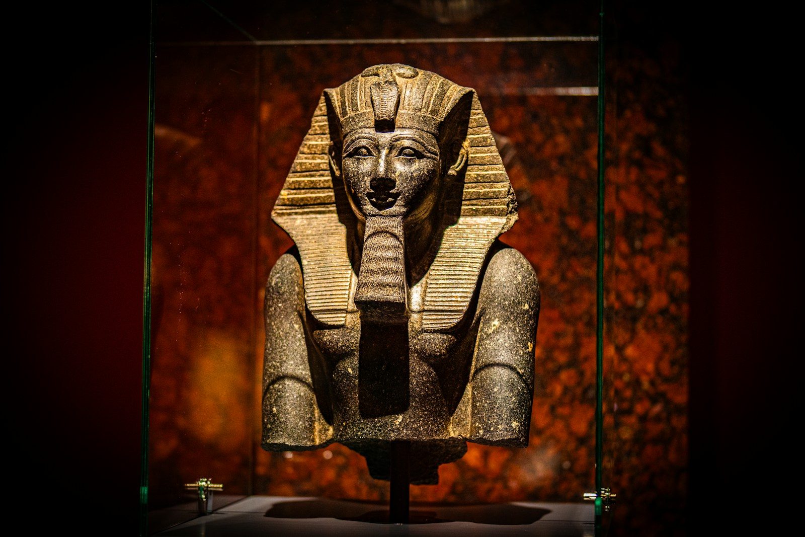 A statue of an egyptian god in a glass case