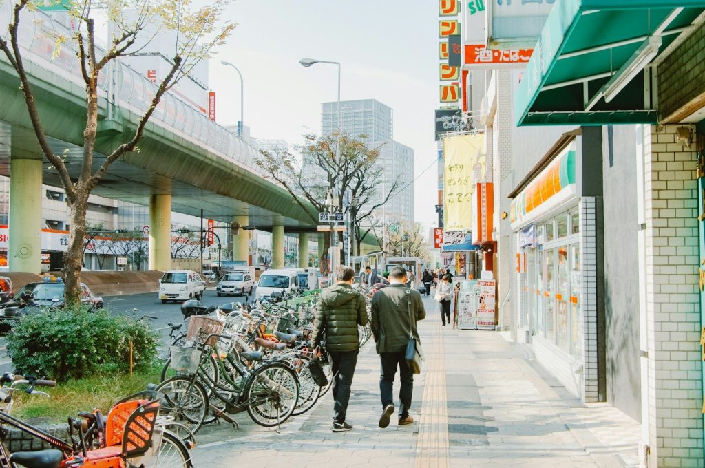 Two people walking on a city sidewalk with parked bicycles.