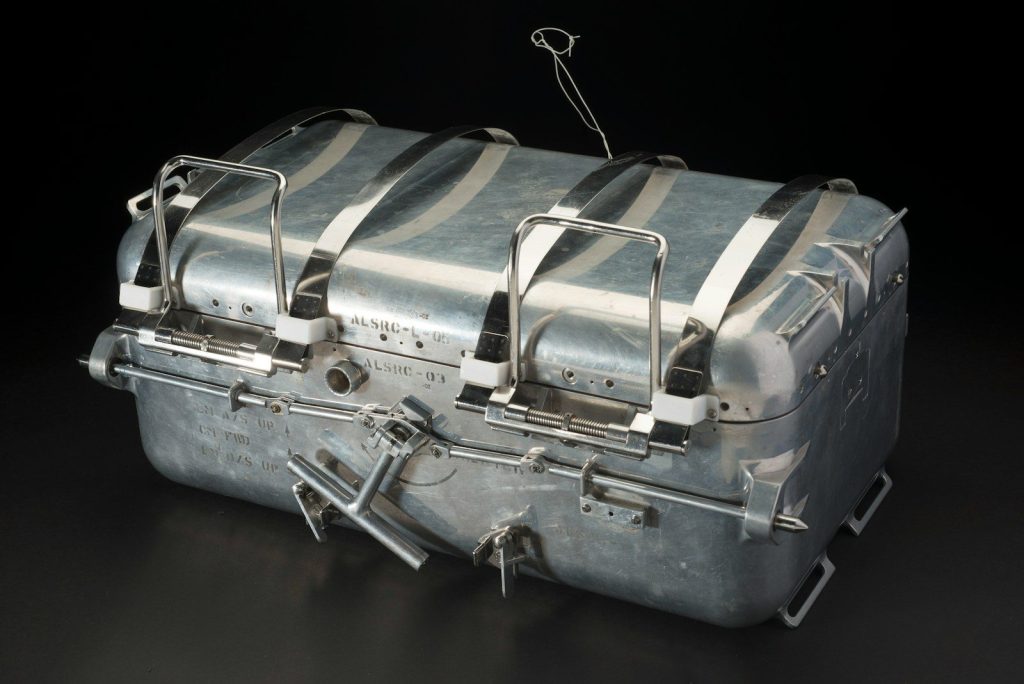 A metallic survival raft on a black background