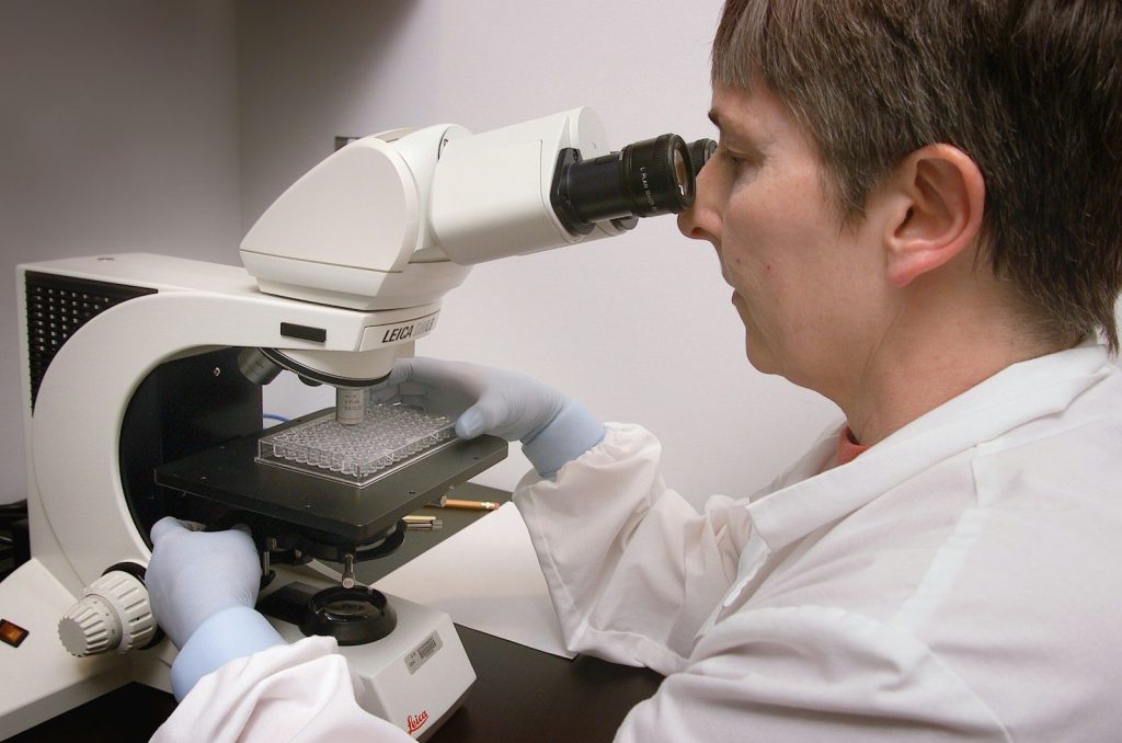 a man in a lab coat looking through a microscope