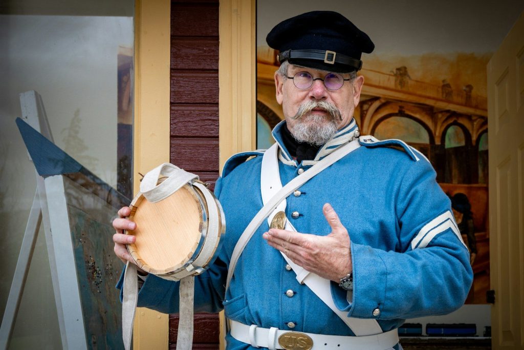 Man in historical military uniform holding a drum.
