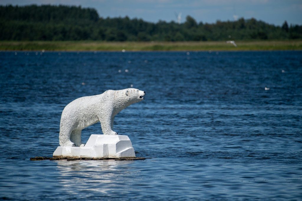 A polar bear sculpture on an ice floe in water.